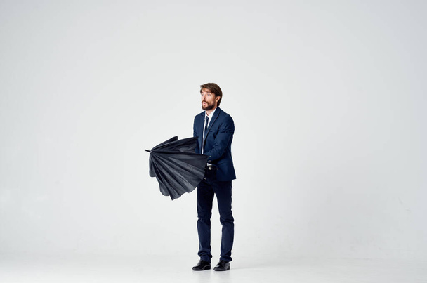 bearded man with a black umbrella and in a suit on a light background in full growth - Photo, Image