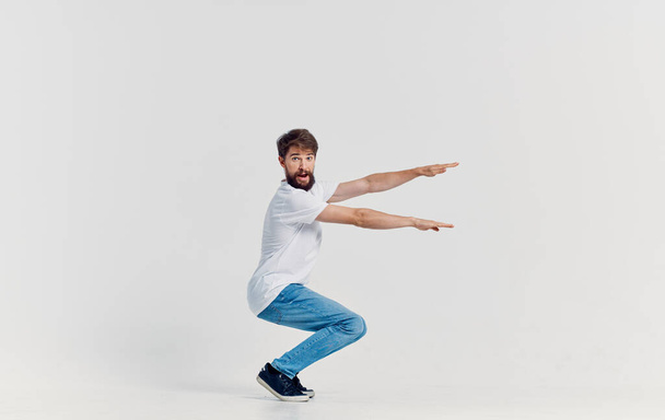 fröhlicher Mann in weißem T-Shirt und Jeans Freizeitkleidung Studio isolierten Hintergrund - Foto, Bild
