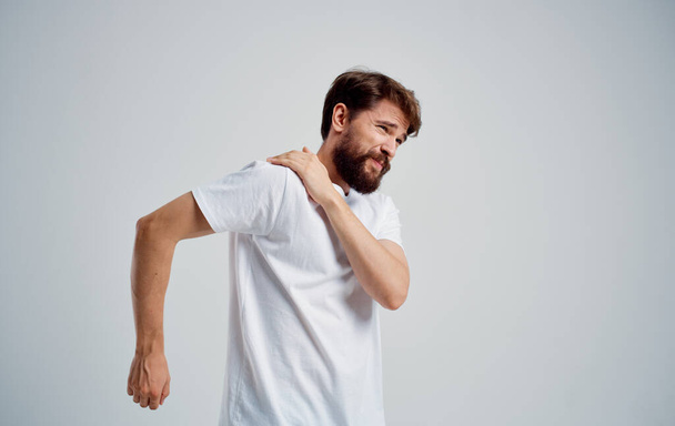 mężczyzna ma ból barku i biały t-shirt przemieszczenie problemy zdrowotne - Zdjęcie, obraz