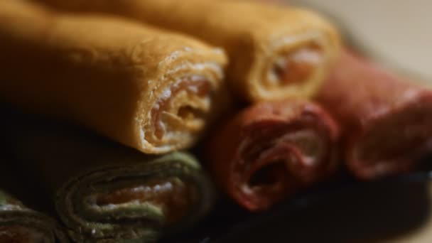 Λεπτές νόστιμες πολύχρωμες τηγανίτες. Μακρο άποψη του κόκκινου, κίτρινου και πράσινου cutaway έλασης τηγανίτες με τυρί κρέμα και γέμιση σολομού σε ένα πιάτο. Βίντεο 4K. Επιβράδυνση - Πλάνα, βίντεο