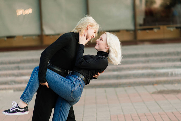 Due giovani femmine che camminano sorridenti abbracciando e baciando all'aperto - Foto, immagini