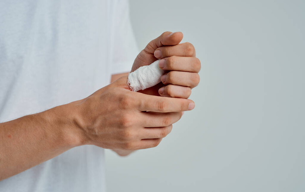 man in wit t-shirt verbonden duim gezondheidsproblemen geneeskunde - Foto, afbeelding
