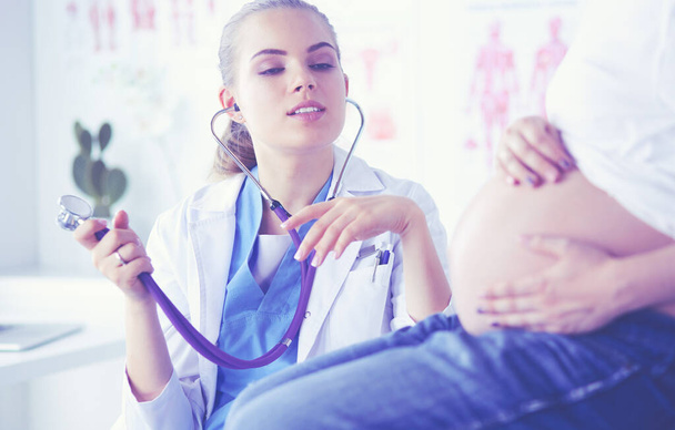 Young woman doctor with stethoscope speaking with pregnant woman at hospital. - Foto, immagini