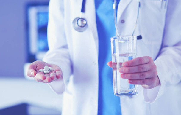 shot of doctors hands holding pills and glass of water at clinic. - Φωτογραφία, εικόνα