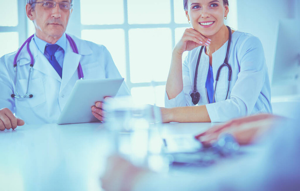 Lächelnde Ärztin mit einem Laptop, die mit ihren Kollegen in einem hellen Krankenhauszimmer arbeitet - Foto, Bild