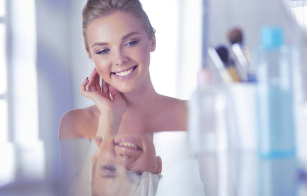 Young woman in bathrobe looking in bathroom mirror - Foto, Imagem