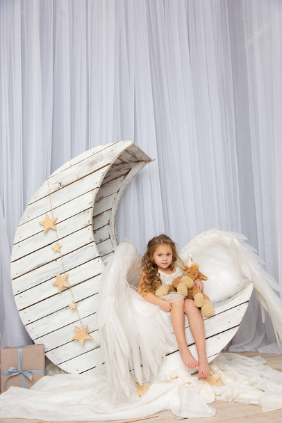 Χριστουγεννιάτικα γυρίσματα ενός χαριτωμένου μικρού κοριτσιού στο στούντιο με φτερά - Φωτογραφία, εικόνα