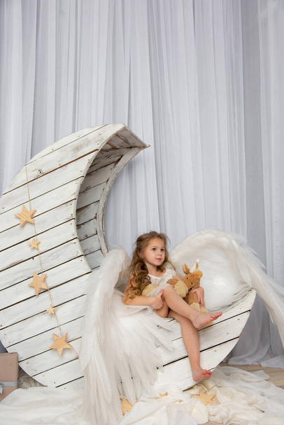 Χριστουγεννιάτικα γυρίσματα ενός χαριτωμένου μικρού κοριτσιού στο στούντιο με φτερά - Φωτογραφία, εικόνα
