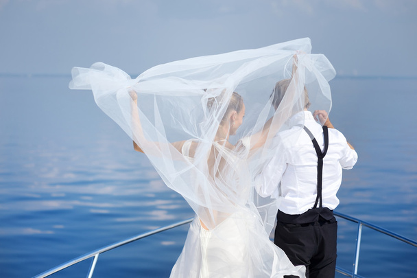 Happy bride and groom on a yacht - Фото, изображение