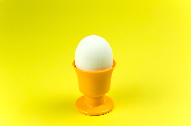 Egg in cup at yellow background - Fotografie, Obrázek