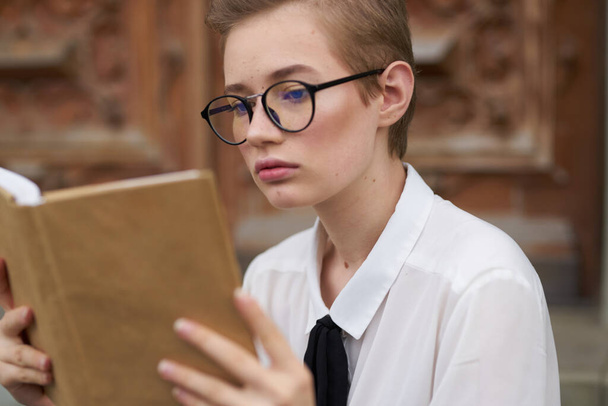 női tanuló szemüvegben egy könyvvel a kezében az Intézet épülete mellett - Fotó, kép