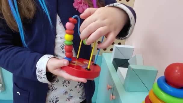 The child plays an educational wooden toy labyrinth. Kids hands playing wire maze and beads. - Footage, Video