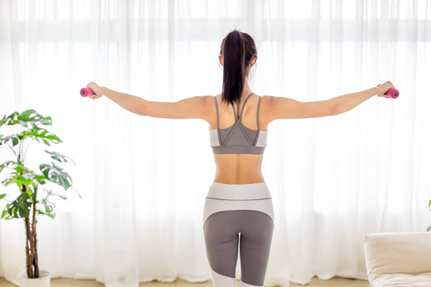  młoda kobieta w odzieży sportowej robi ćwiczenia rozciągające fitness z hantlami w domu - Zdjęcie, obraz