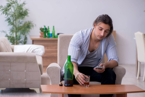 młody mężczyzna alkoholik oglądanie TV po imprezie - Zdjęcie, obraz