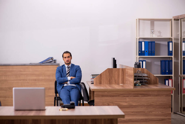 Fiatal férfi alkalmazott ül a munkahelyen - Fotó, kép