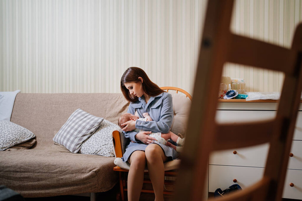 Mother breastfeeds a newborn at home on the couch. the benefits of breastfeeding - Photo, image