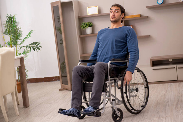 Jeune homme en fauteuil roulant souffrant à la maison - Photo, image