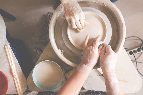 陶芸家の車輪の上に陶器のカップを作る女性の手。手作り・ものづくりのコンセプト.  - 写真・画像