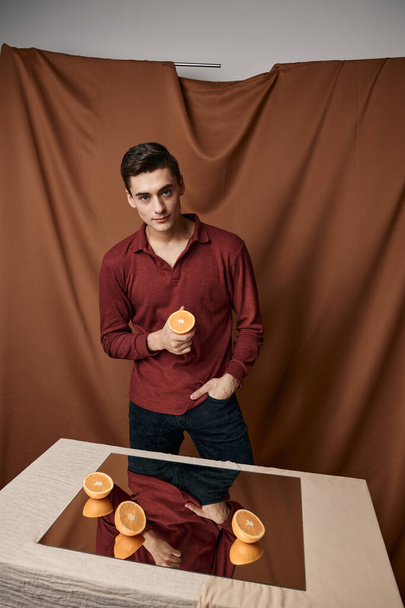 Sliced oranges on the table and reflective mirror man fabric background - Valokuva, kuva