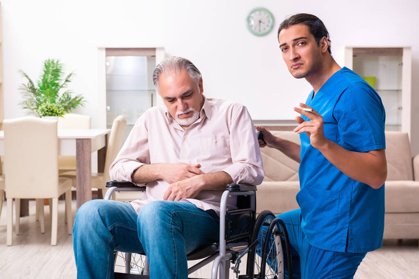 車椅子の老人と屋内の若い悪い介護者 - 写真・画像