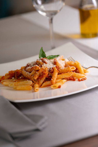 close up of an appetizing plate of macaroni with bolognese sauce and grated cheese. - Foto, Imagem