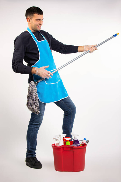 Gender stereotypes and good mood. A man at home dancing with a mop on a white background. High quality photo - Fotó, kép