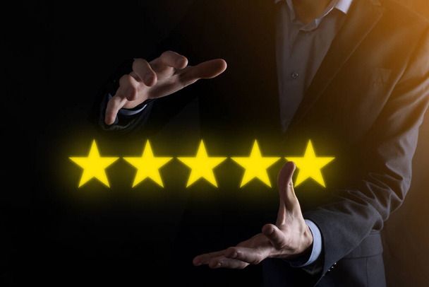 Man Hand zeigt auf fünf Sterne ausgezeichnete Bewertung.Zeigen fünf Sterne Symbol, um die Bewertung des Unternehmens zu erhöhen.Bewertung, Erhöhung der Bewertung oder des Rankings, Bewertung und Klassifikationskonzept. - Foto, Bild