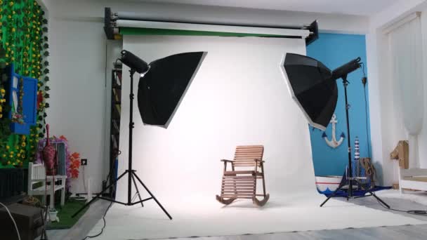 Altı köşeli stüdyo ışıkları olan fotoğraf ya da video stüdyosu. Beyaz ekran ve sallanan sandalye - Video, Çekim