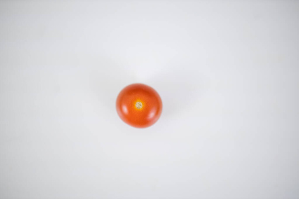 One cherry tomato isolated on a white table - Zdjęcie, obraz