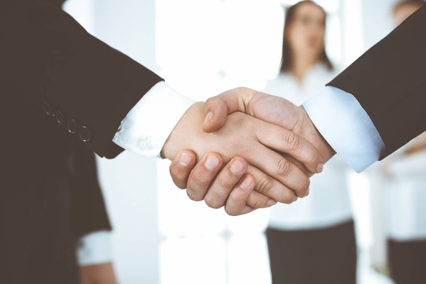 Businessman and woman shaking hands in office. Concept of handshake as success symbol in business - Fotografie, Obrázek