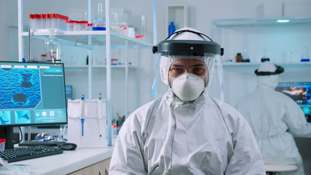 Orvos férfi néz kamera ül a laborban öltözött ppe öltöny - Fotó, kép
