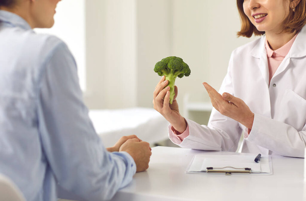 Nutritionist telling woman about benefits of healthy diet and recommending eating vegetables - Foto, Imagem