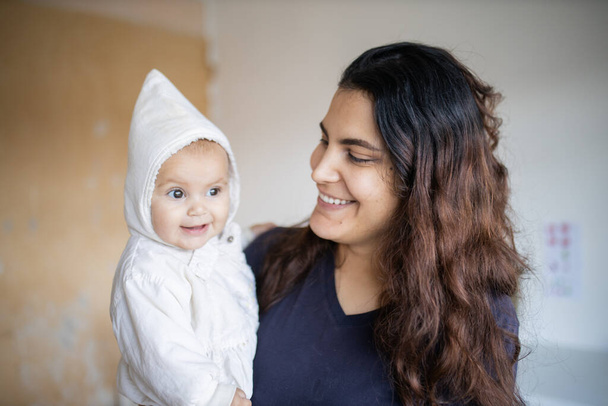Щаслива жінка тримає свою чарівну дитину в білому одязі
 - Фото, зображення