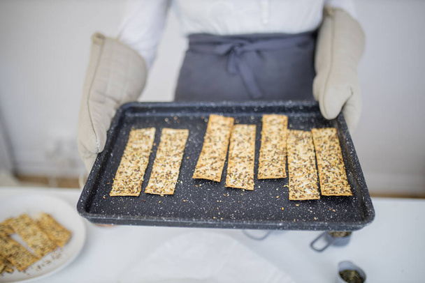Mãos de luva segurando uma bandeja preta de pão crocante sueco - Foto, Imagem