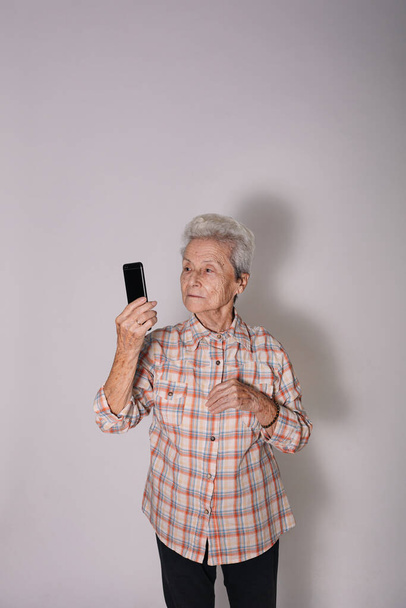 Nagymama néz egy okostelefon. - Fotó, kép