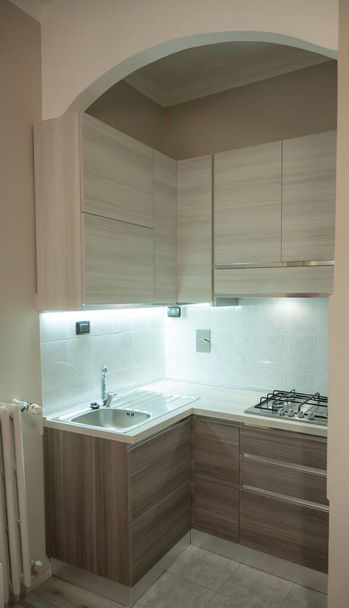 Näkymä modulaarinen kulma keittiö harmaa ja ruskea väri, led alle kaappi valo herättää huomiota. - Valokuva, kuva