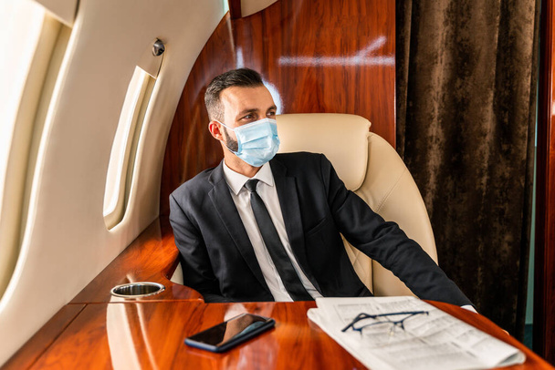 Handsome businessman wearing elegant suit  flying on exclusive private jet - Successful entrepreneur sitting in exclusive business class on airplane, concepts about business and trasportation - Fotó, kép