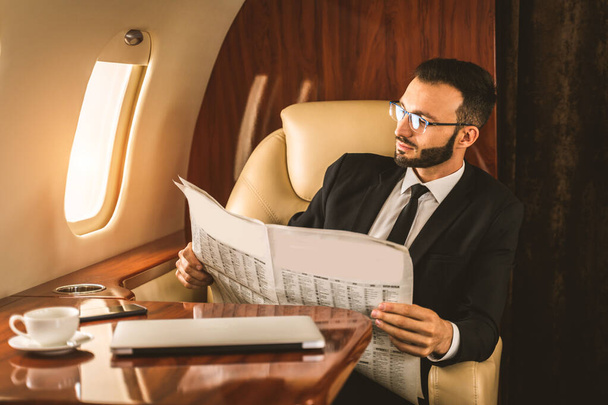 Handsome businessman wearing elegant suit  flying on exclusive private jet - Successful entrepreneur sitting in exclusive business class on airplane, concepts about business and trasportation - Фото, изображение