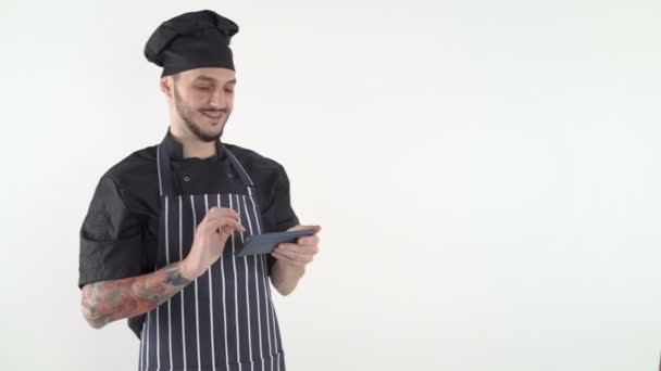 Chef en uniforme escribiendo en el teléfono inteligente sobre fondo blanco - Imágenes, Vídeo