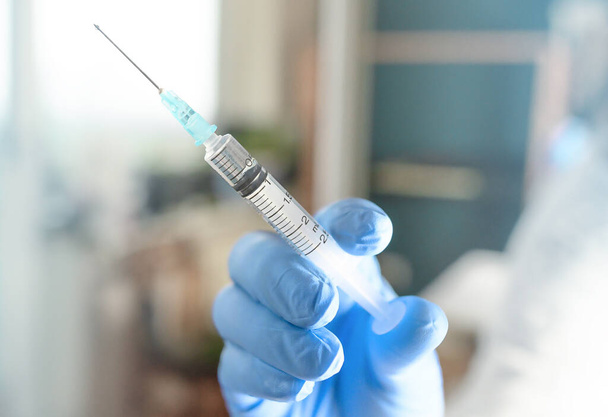 Gesundheitspflegekonzept. Ein Arzt hält einen Impfstoff in blauen medizinischen Handschuhen bereit. während der Coronavirus-Krise, Covid 19 Virus. Hochwertiges Foto - Foto, Bild