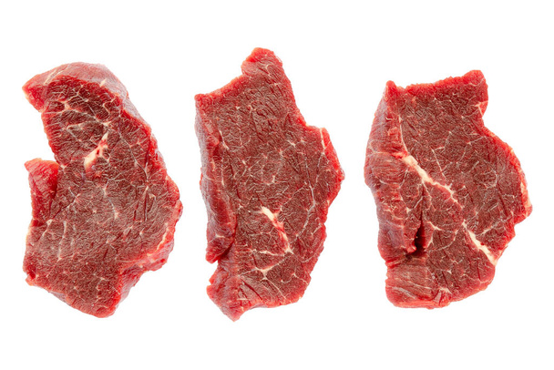 Three pieces of beef meat isolated on white background, clipping path, top view. Pieces of buffalo meat close-up, top view. Pieces of beef for steak. Fresh raw cuts of beef. Fresh beef slices. - Photo, Image