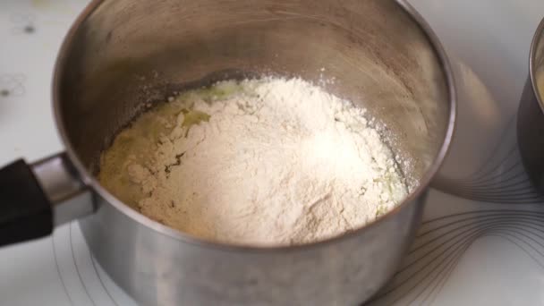 Bakken van bechamelsaus. De bloem en warme melk worden toegevoegd aan de gesmolten boter.  - Video