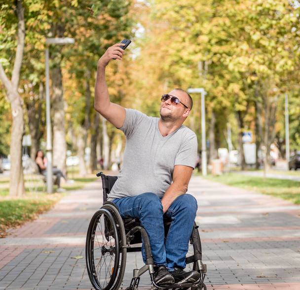 Handicapped man in wheelchair at the park alley use a smartphone - Fotografie, Obrázek