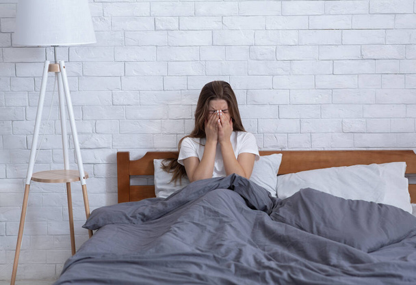 Нещасна молода жінка плаче сама в ліжку вдома, сумуючи за втратою коханої людини
 - Фото, зображення