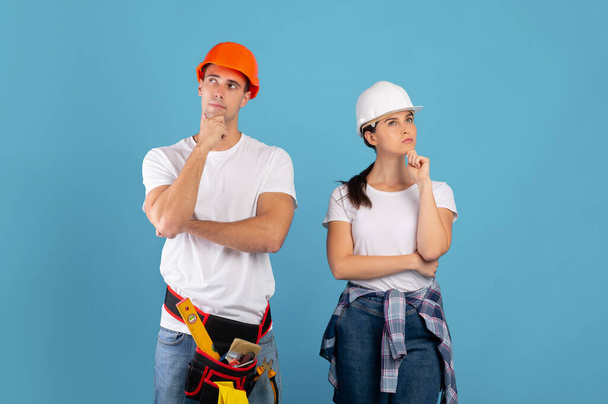 Renovatieplanning. Portret van Pensive Young Couple in beschermende harde hoeden - Foto, afbeelding