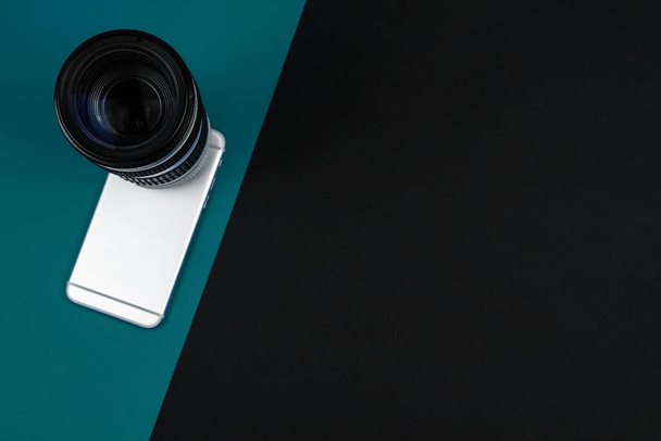 Smartphone concept met camera DSLR lens, eenvoudige platte getijdenwater groene achtergrond, kopieerruimte, banner, apparatuur foto - Foto, afbeelding