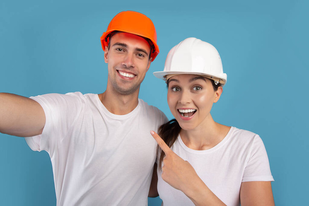 Repair Home Konzept. Junges Paar mit Schutzhelmen macht gemeinsam Selfie - Foto, Bild