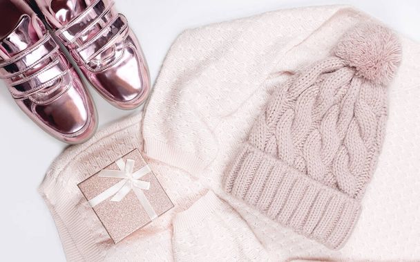 pastel pink women's pillover, shiny sneakers and hat flat lay. cold season female outfit. delicate color for teenager apparel. pink gift box.  - Photo, Image