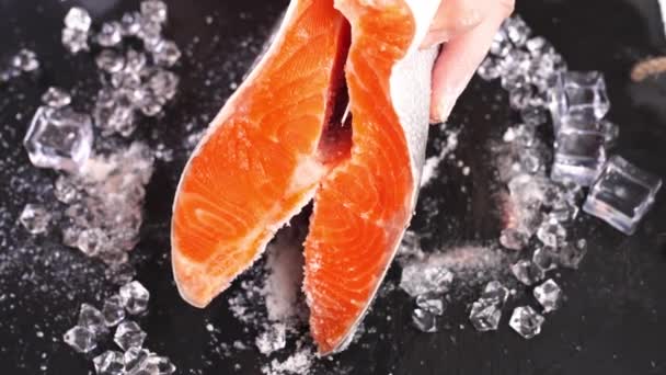 fresh rainbow trout is salted on a black table with ice - Footage, Video