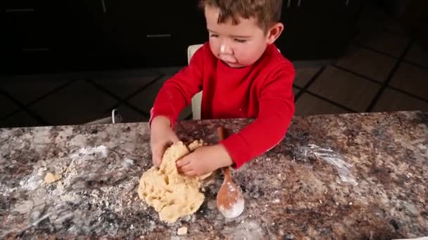 L'enfant pétrit la pâte avec ses mains dans la cuisine. Vidéo de haute qualité - Séquence, vidéo